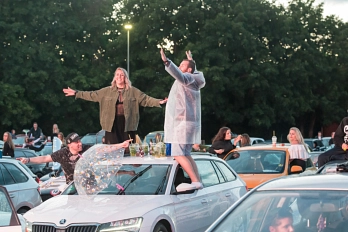 Foto einer Autodisco. Im Hintergrund sind Bäume, davor stehen eng beieinander viele Auto. Auf den Autos stehen Getränke und Menschen. Auf dem vorderen Auto tanzen drei Personen.&nbsp;&copy;&nbsp;Niklas Richter